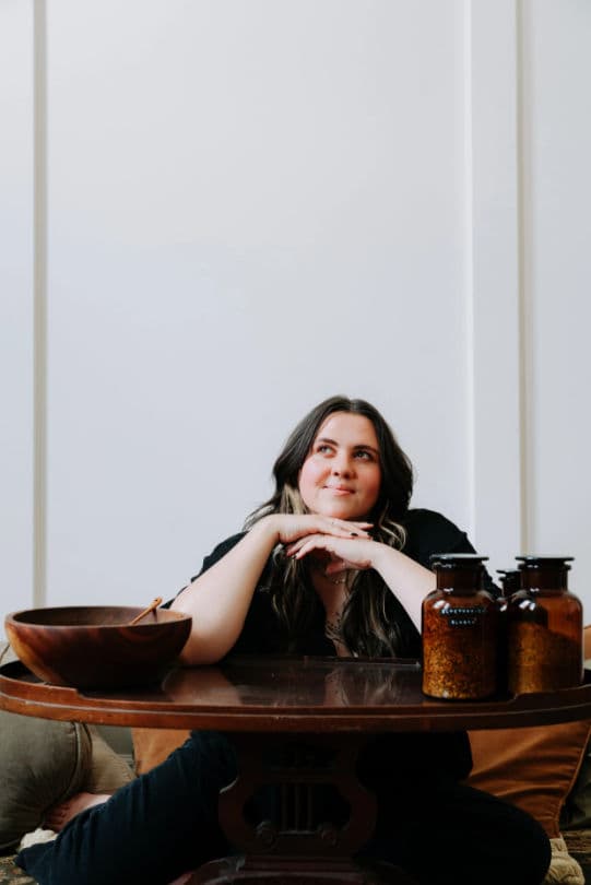 Posed portrait of a person seated at a table with decorative objects.