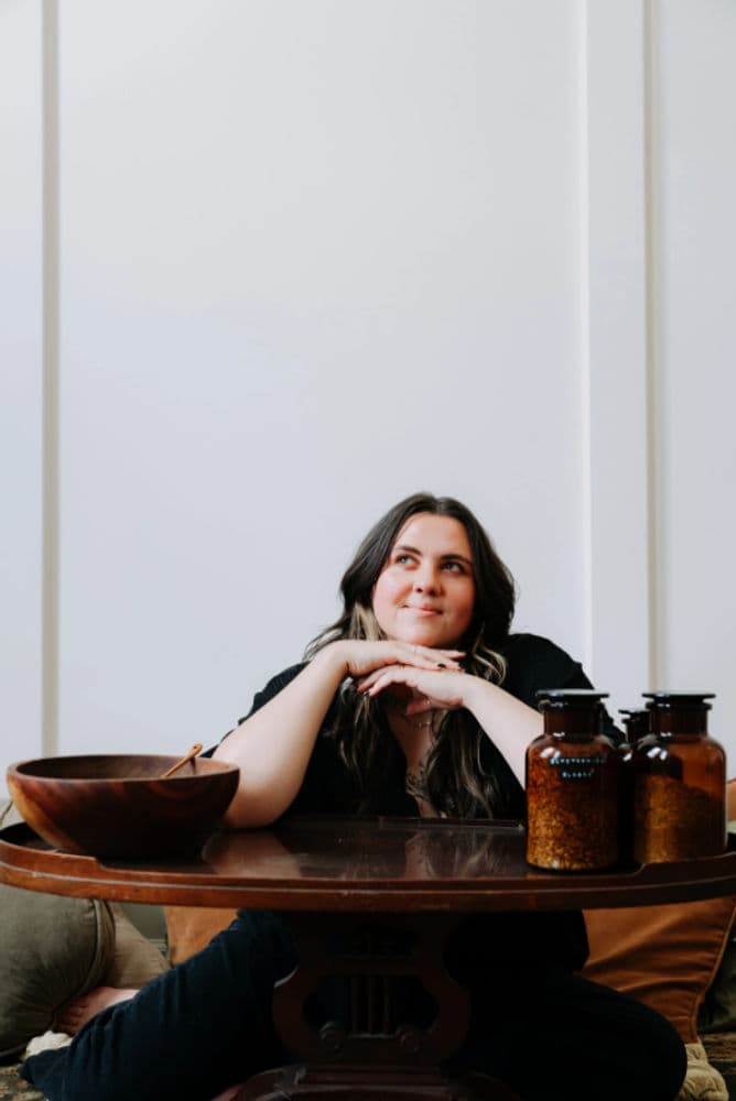 Portrait photograph of a person posed at a table with bowls and glass jars.