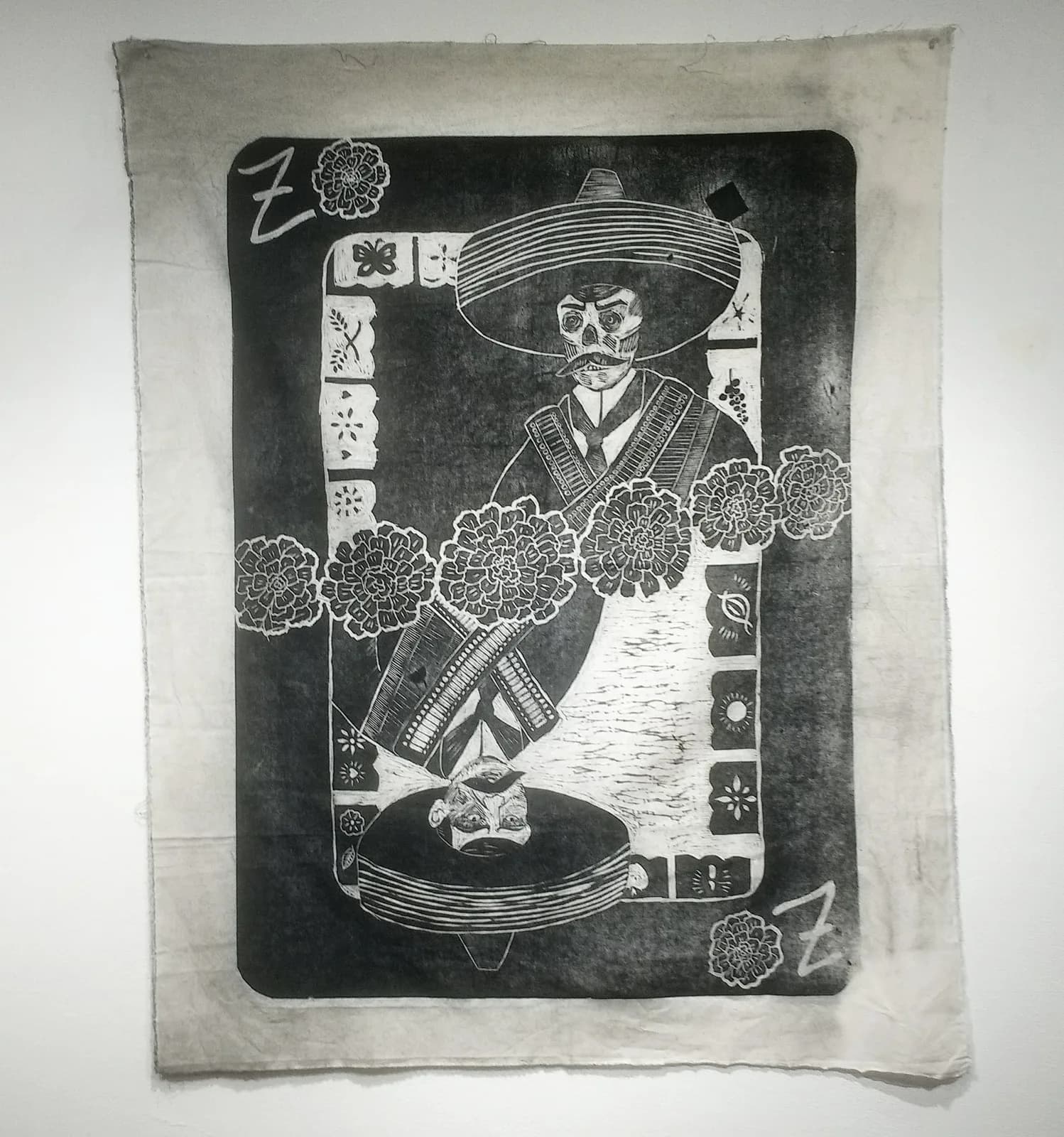 A man in a wide sombrero and patterned vest, surrounded by marigolds, rendered as a bold black-and-white woodcut print.