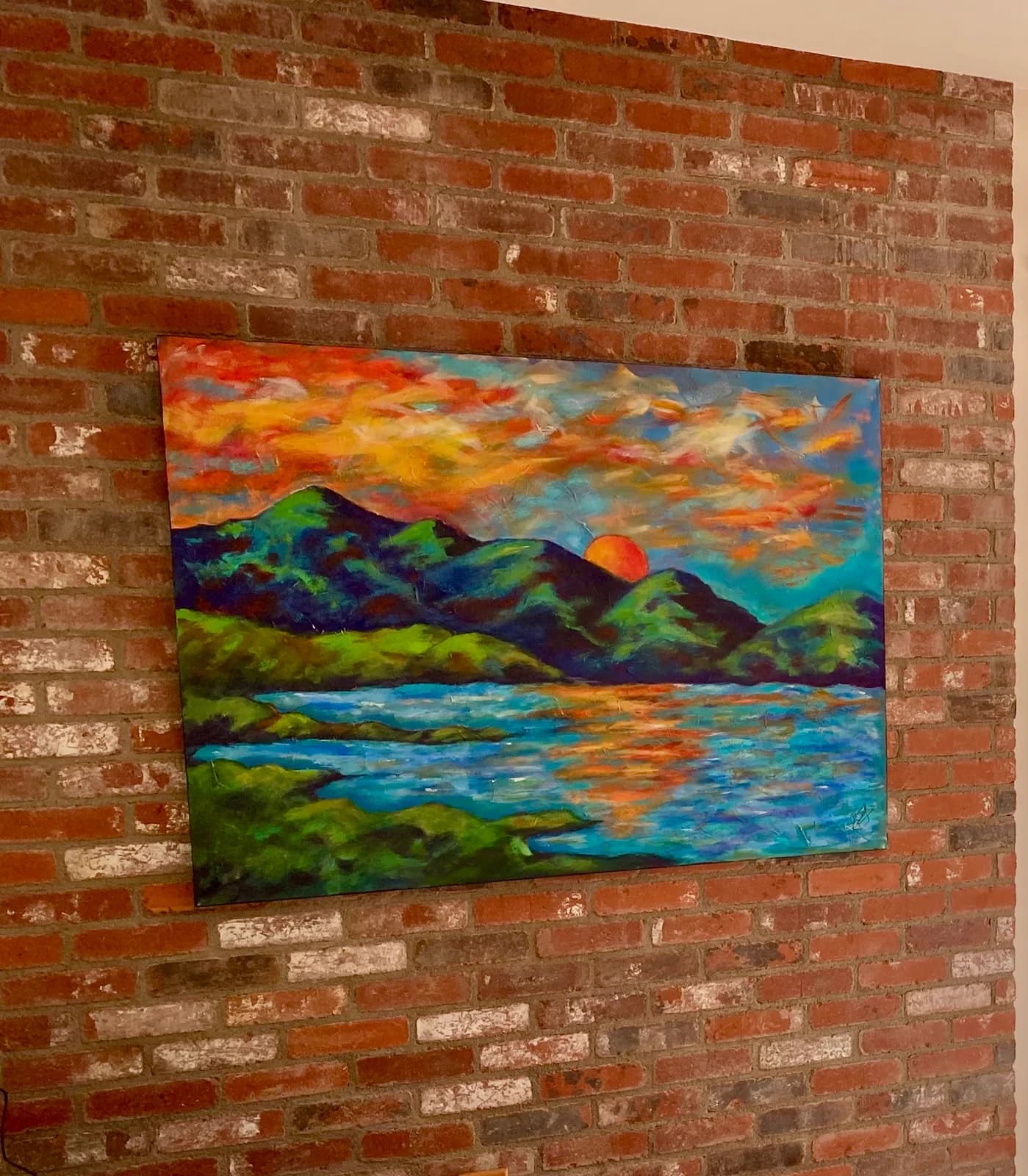 Acrylic landscape painting of mountains, water, and dramatic sunset sky with vivid oranges and blues.