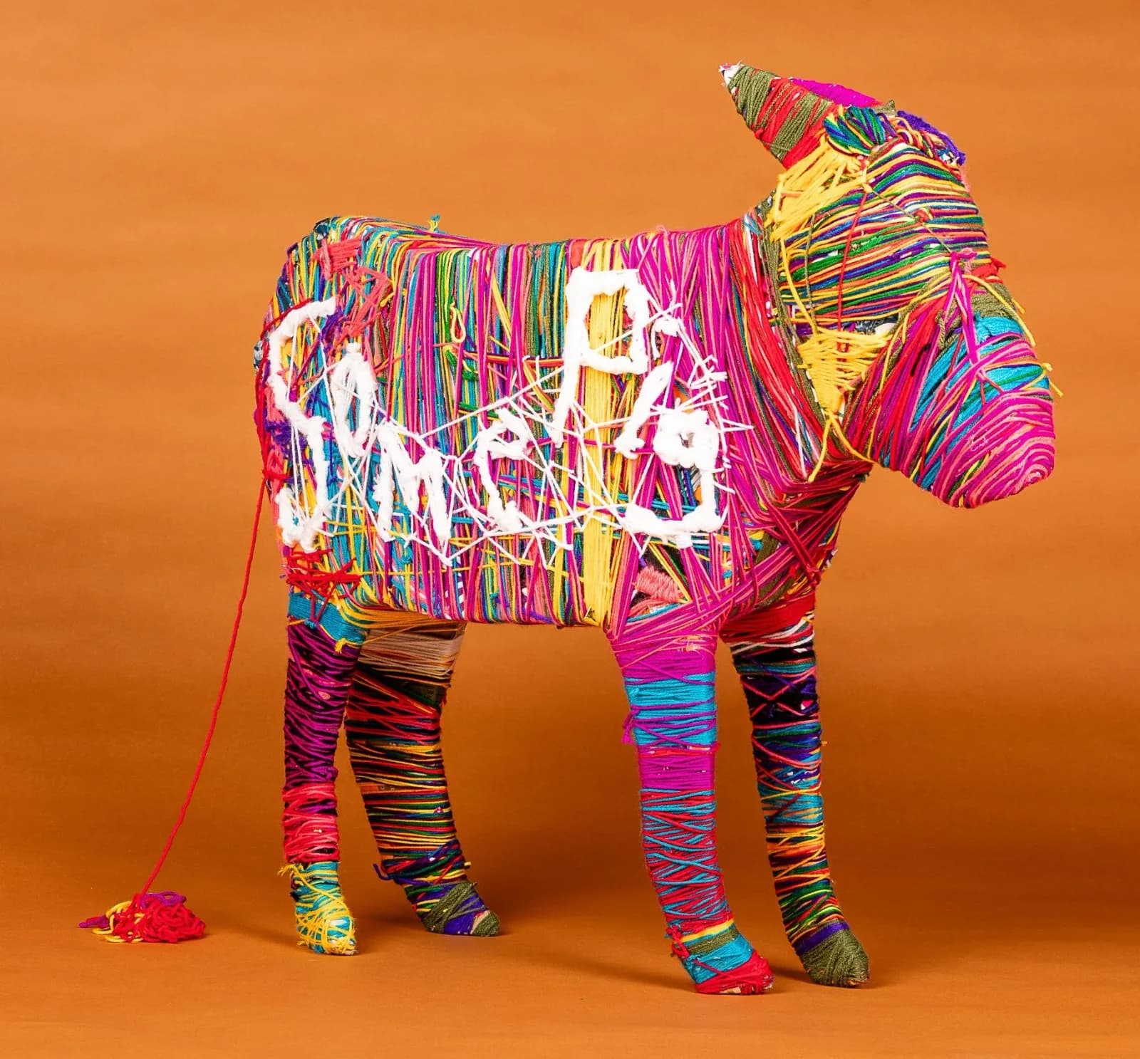 Colorful fiber-wrapped bull sculpture with vibrant multicolor striped yarn against an orange background.