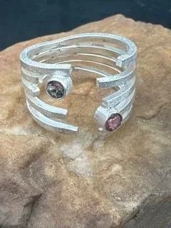 Contemporary silver cuff ring with geometric bands and set gemstones.