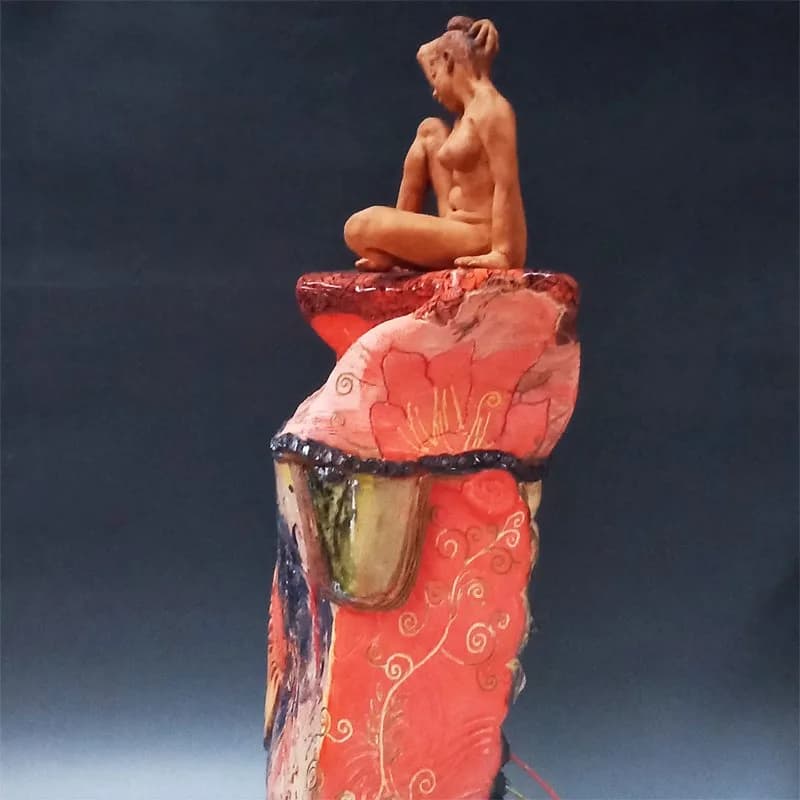 Ceramic and mixed-media stacked sculptural figure with a seated nude torso atop decorative vessel elements.