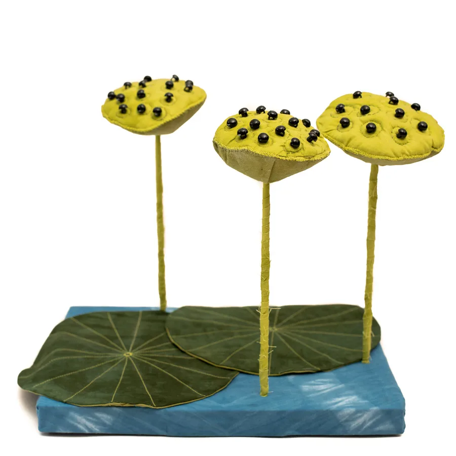 Three-dimensional fabric water lilies with beaded centers rest on a sculptural base.