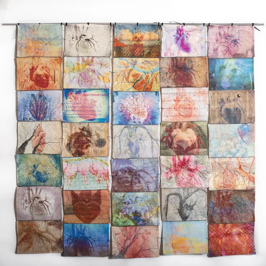 Hanging textile installation of dyed and printed fabric squares featuring layered spider and floral motifs.