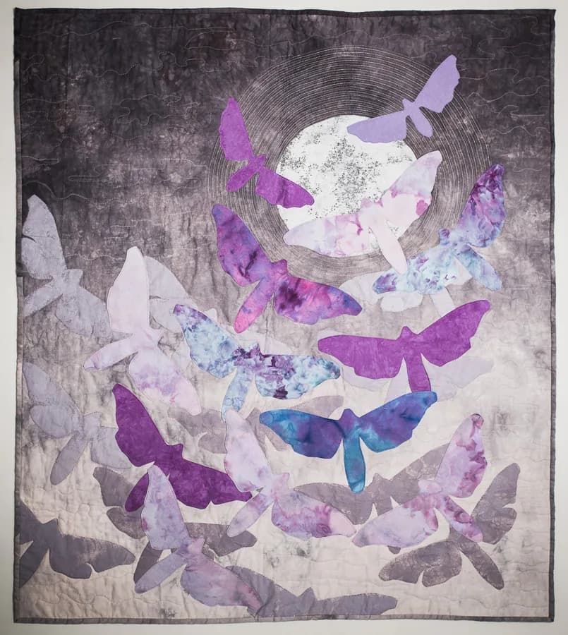Layered fiber textile composition featuring watercolor and ink butterflies arranged around a circular element.