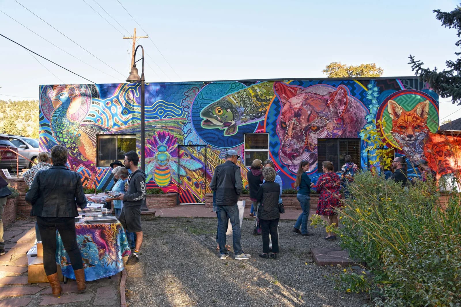 Vibrant street art mural featuring layered imagery of fish, wildlife, and geometric patterns in bold blues and earth tones.