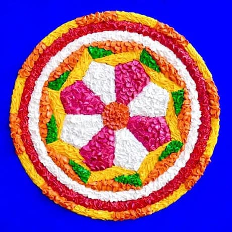 Concentric circles in pink, yellow, orange, and white fiber arranged symmetrically against a blue background.
