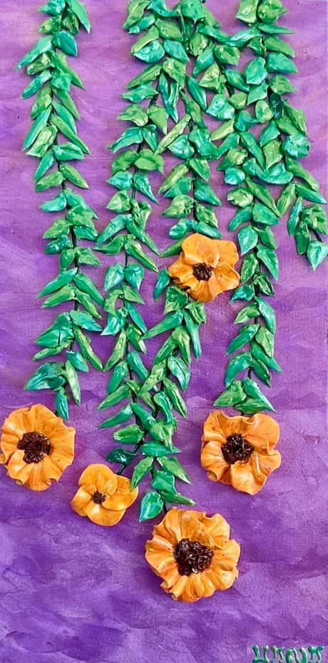 Pressed yellow flowers and green leafy stems arranged on a vibrant purple textile surface.