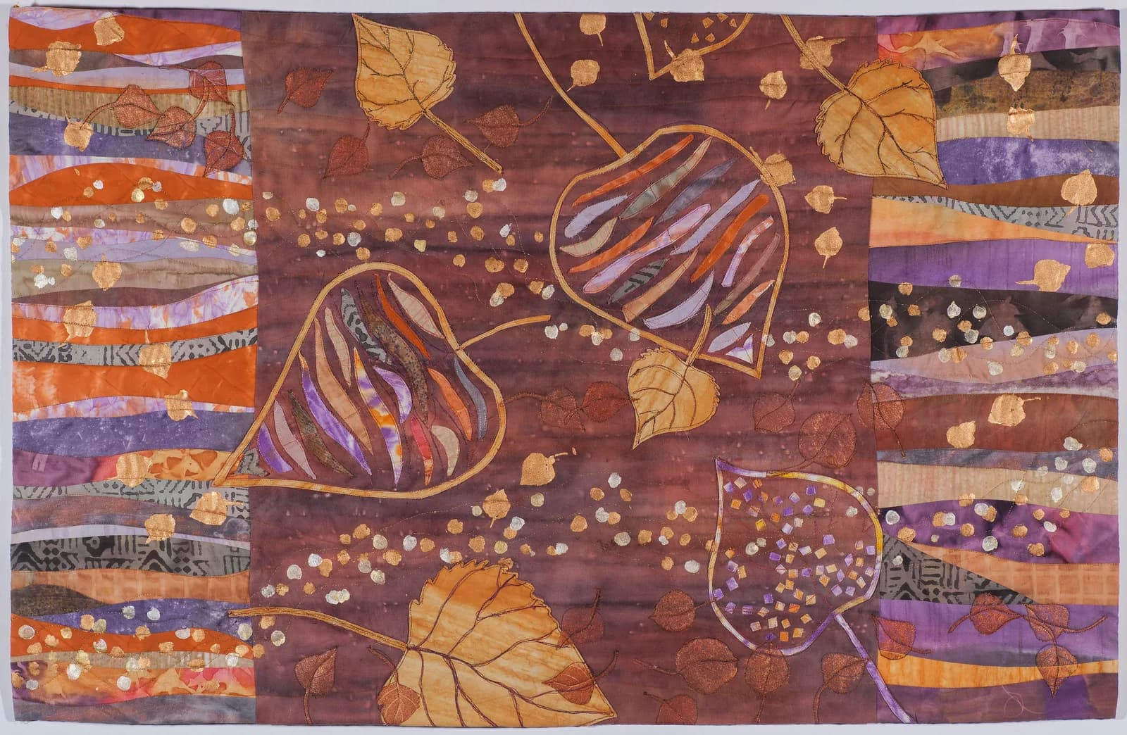 Abstract fiber art featuring stylized seed pods and autumn leaves on a dark patchwork ground.