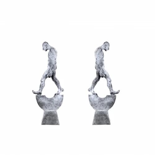Pair of abstract bronze figures in mirrored poses, each balanced on a concave curved base.