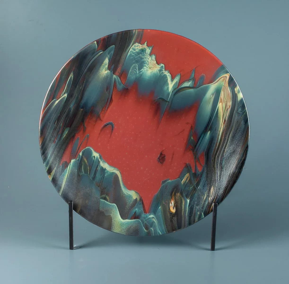 Circular ceramic vessel with encaustic volcanic landscape, red oxide surface, and mineral-toned relief forms.