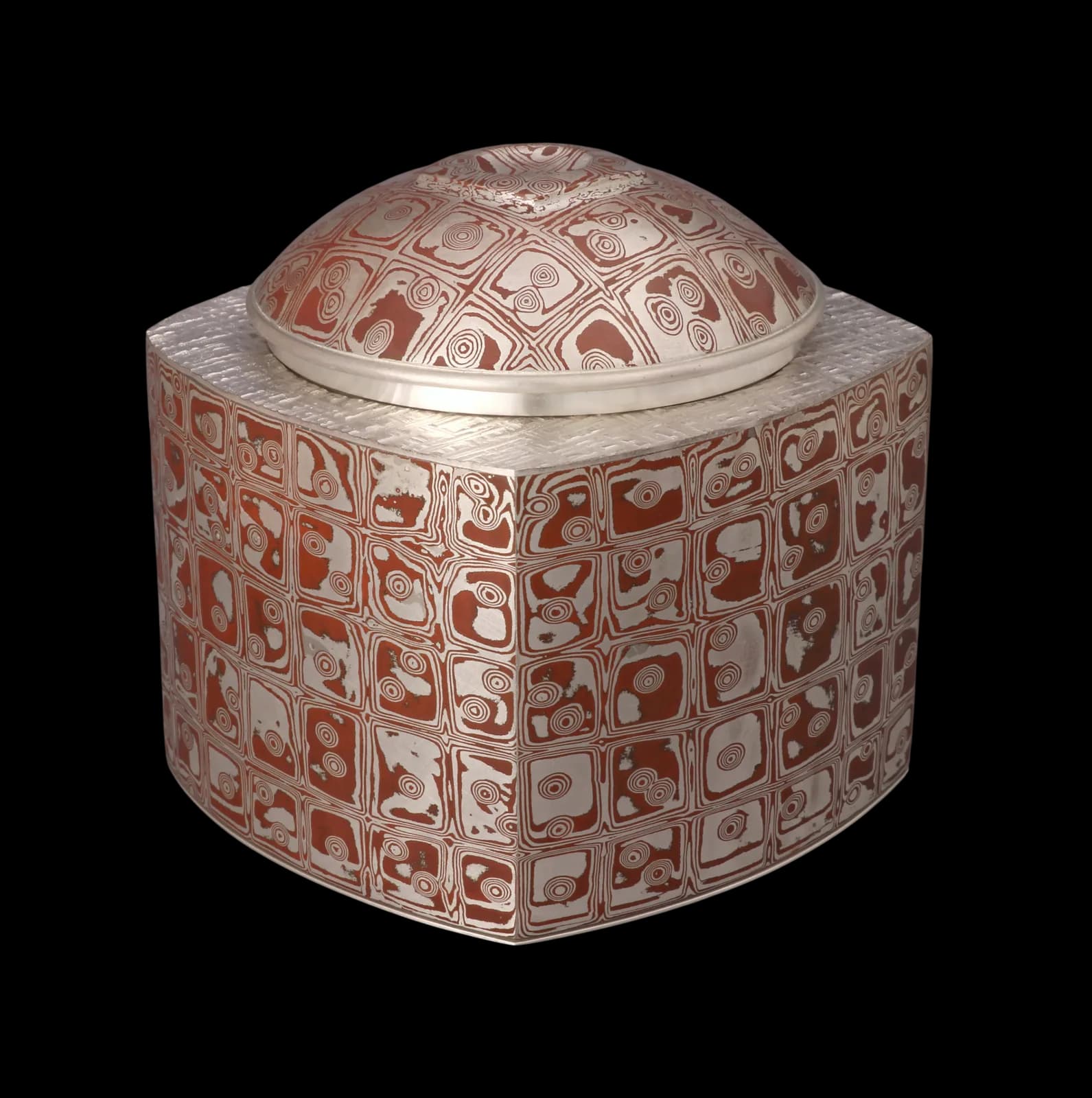 A lidded ceramic vessel with patterned red and white glaze and geometric pictographic motifs.