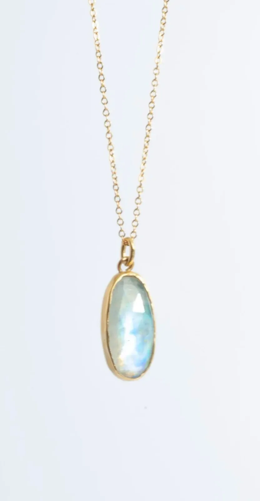 Gold-bezel pendant with opalescent moonstone on delicate chain.
