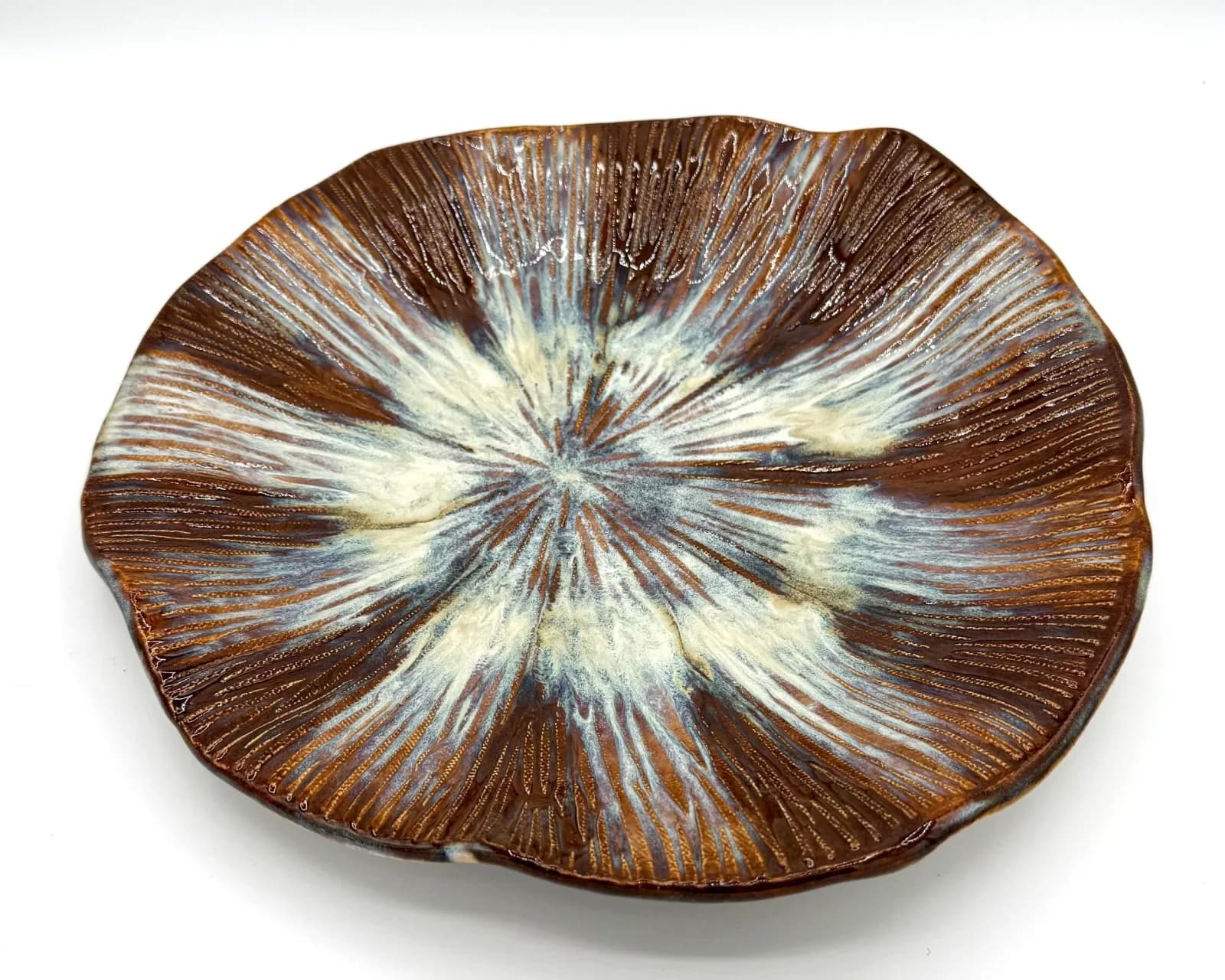 Ceramic bowl with radial glaze pattern in browns, creams, and blue tones.