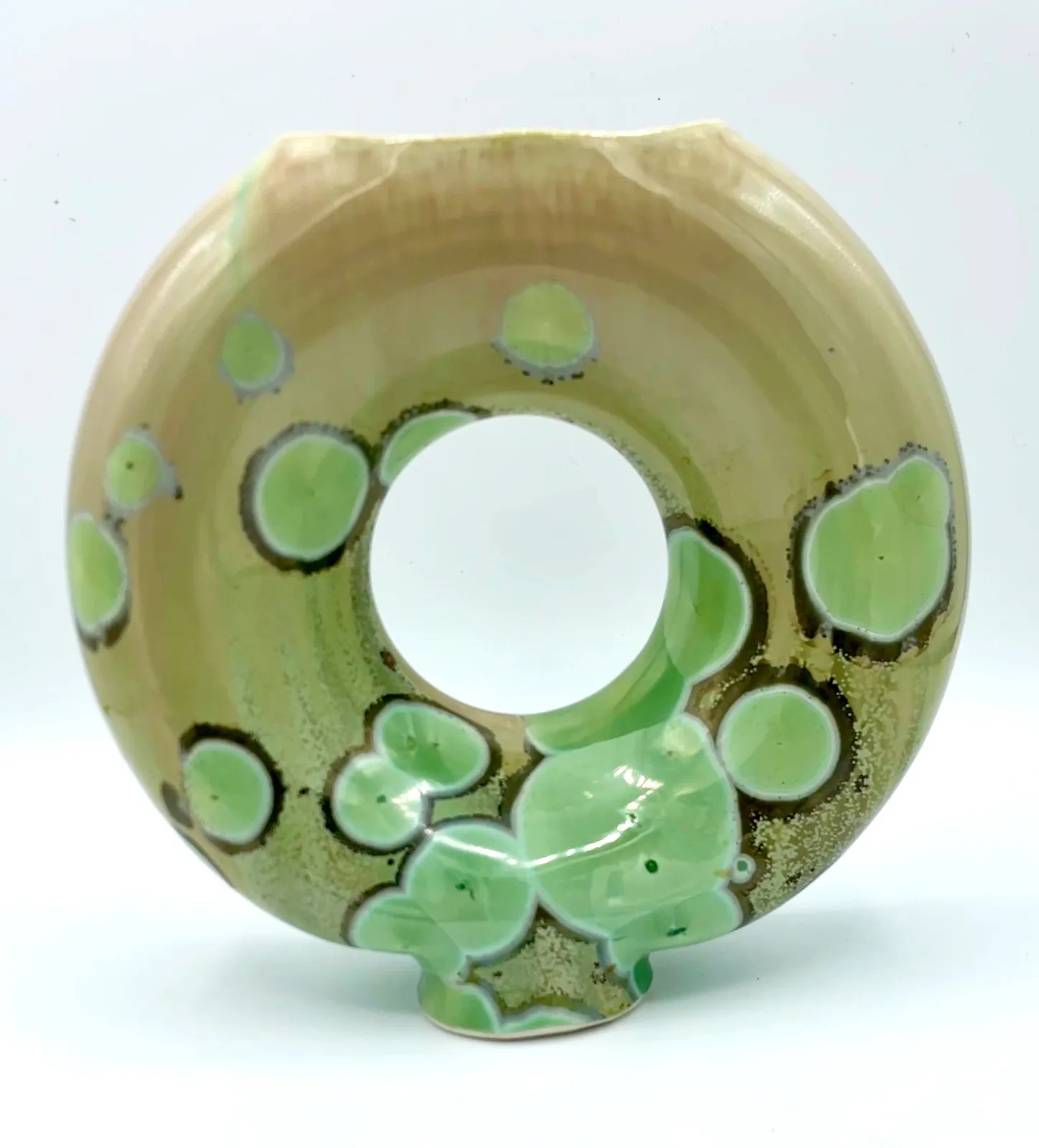 Abstract ceramic sculptural vessel with organic circular forms and green glaze accents.