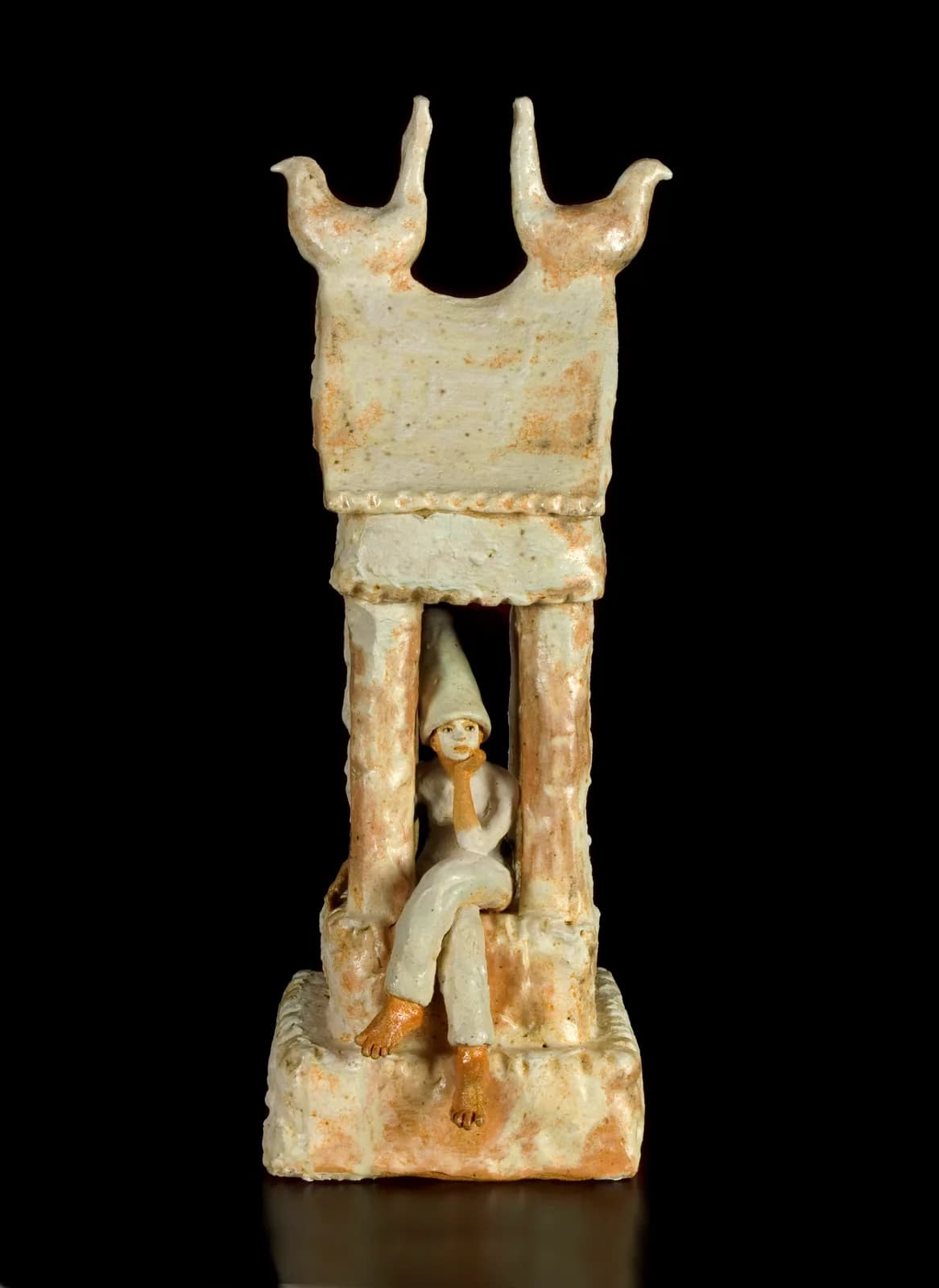 Carved stone sculpture of a seated figure sheltered within an ornamental tower form with bird finials.