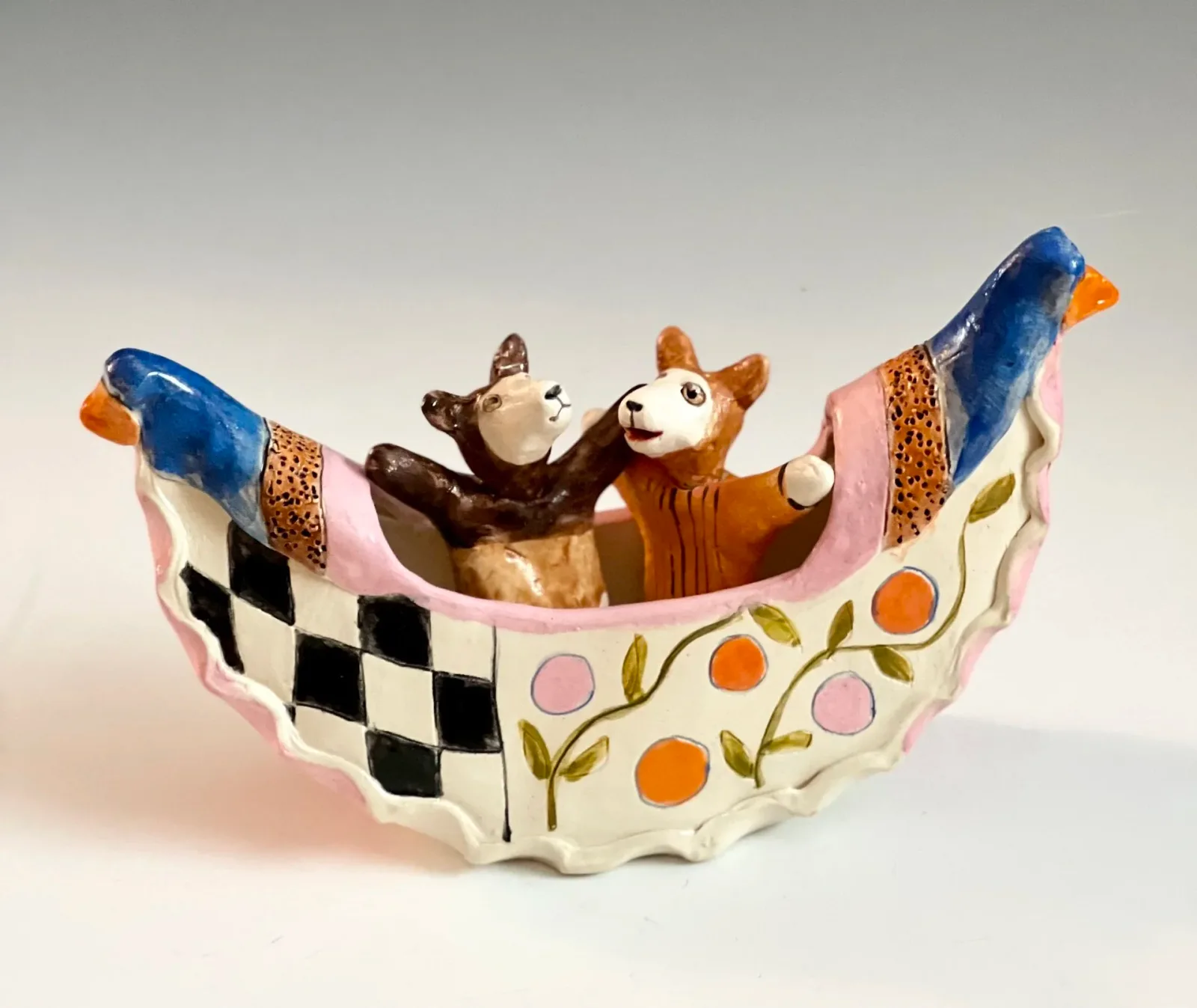 Hand-painted ceramic vessel with two bears in a hammock, decorated with harlequin and floral motifs.