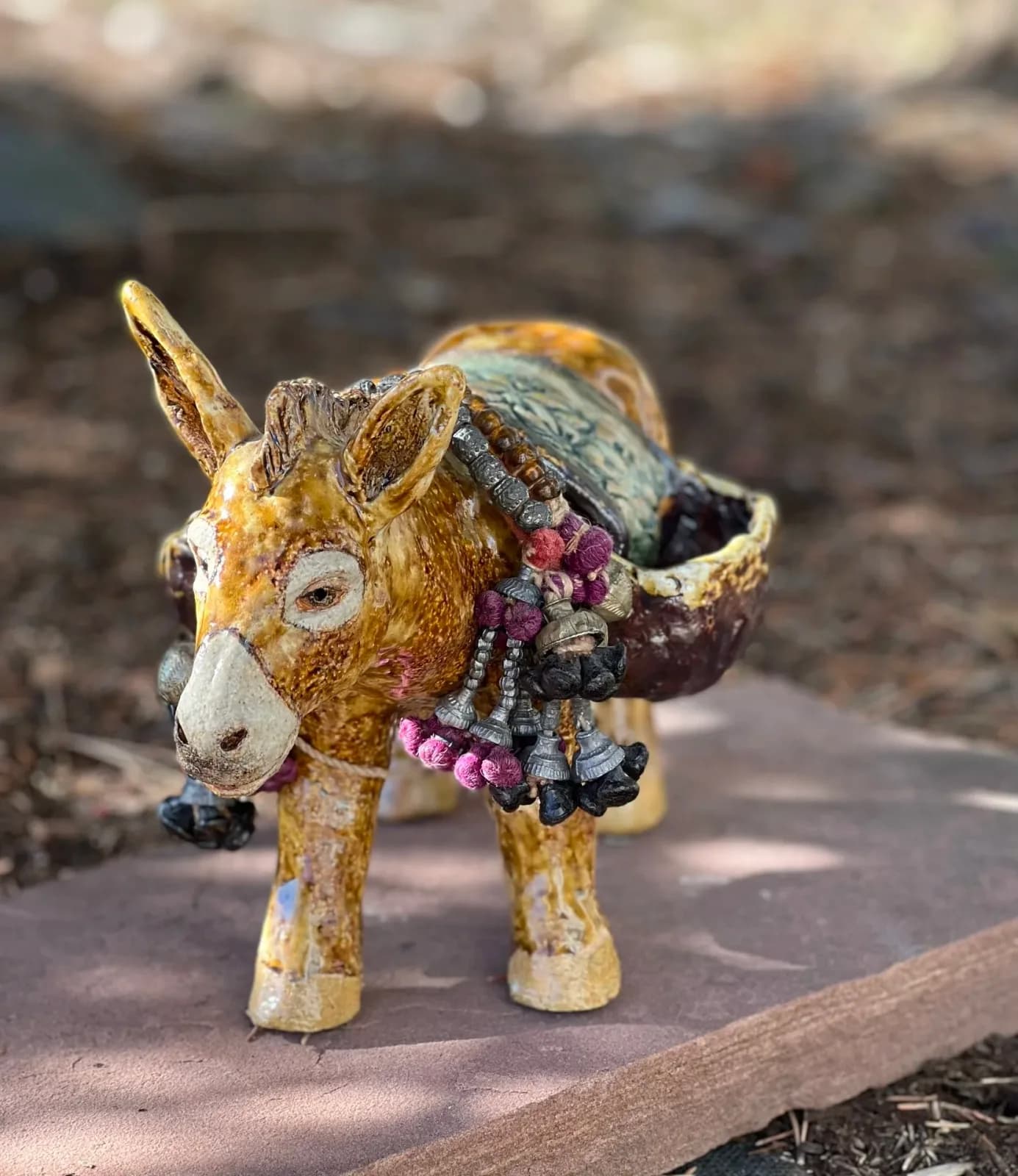 Hand-painted ceramic goat figurine with beaded decorative saddle and blanket detailing.
