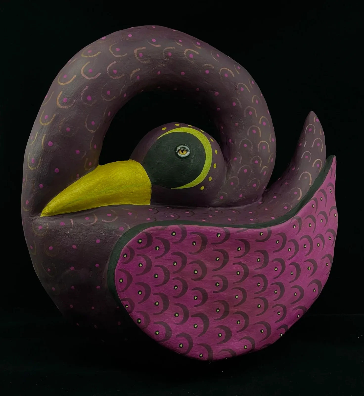 Carved wooden sculpture with purple and yellow details, featuring abstracted curved forms and incised patterns.