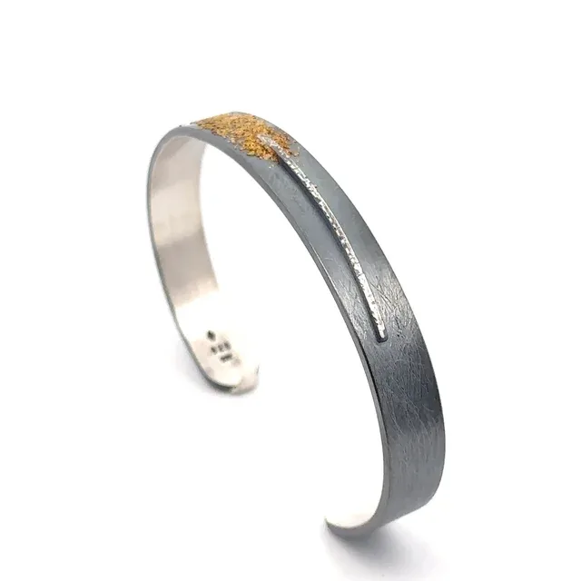 Mixed-metal cuff bracelet with oxidized silver and gold accent detail.
