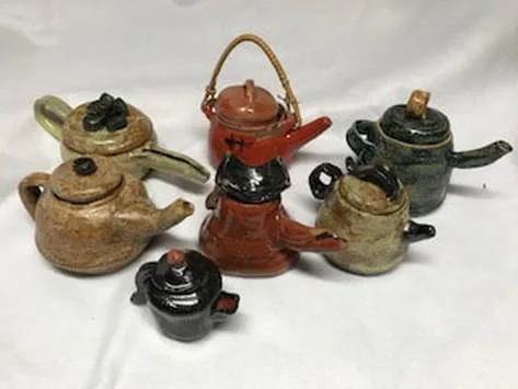 Handmade ceramic teapots and vessels in earthy, glazed tones arranged as a still life composition.