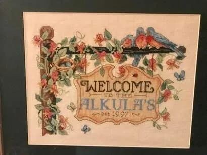 Embroidered textile with wildflower border and "Welcome" text in folk style, dated 1995–1997.