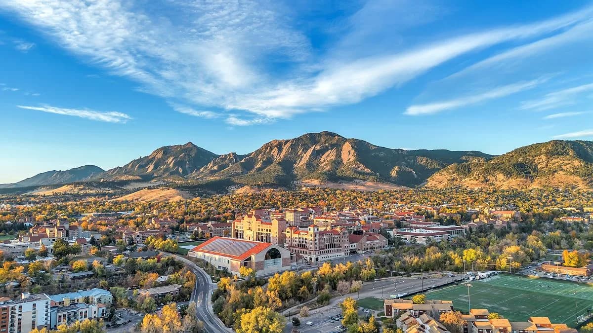 Aerial photograph of Boulder with the distinctive tilted Flatirons rising above the city at golden hour.