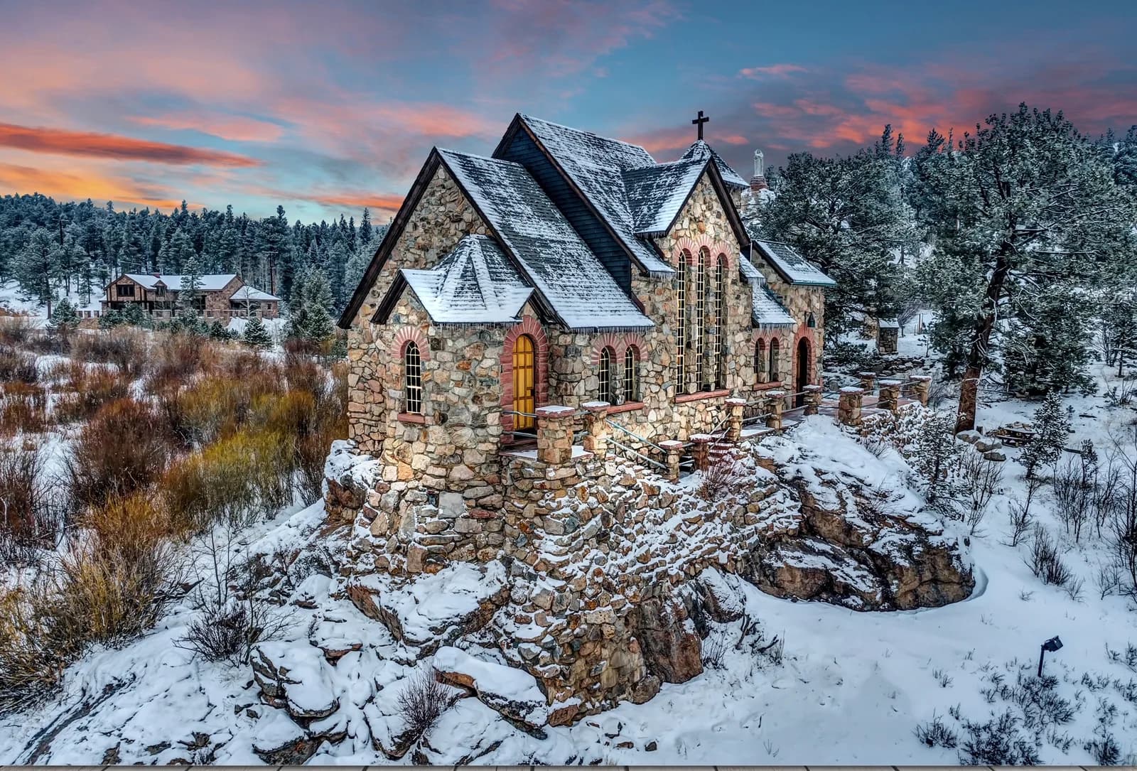 Stone chapel perched on a snowy ridge at sunset, surrounded by winter forest and golden light.