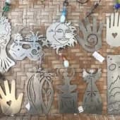 Mixed-media collage combining found objects, gears, and hand imagery on a brick-patterned ground.