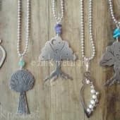 Handmade fiber ornaments with birds and natural forms, suspended from beaded strings.