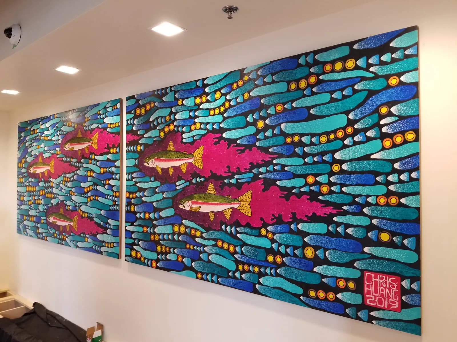 A two-panel mural depicts schools of stylized fish in turquoise, blue, and magenta against patterned backgrounds.
