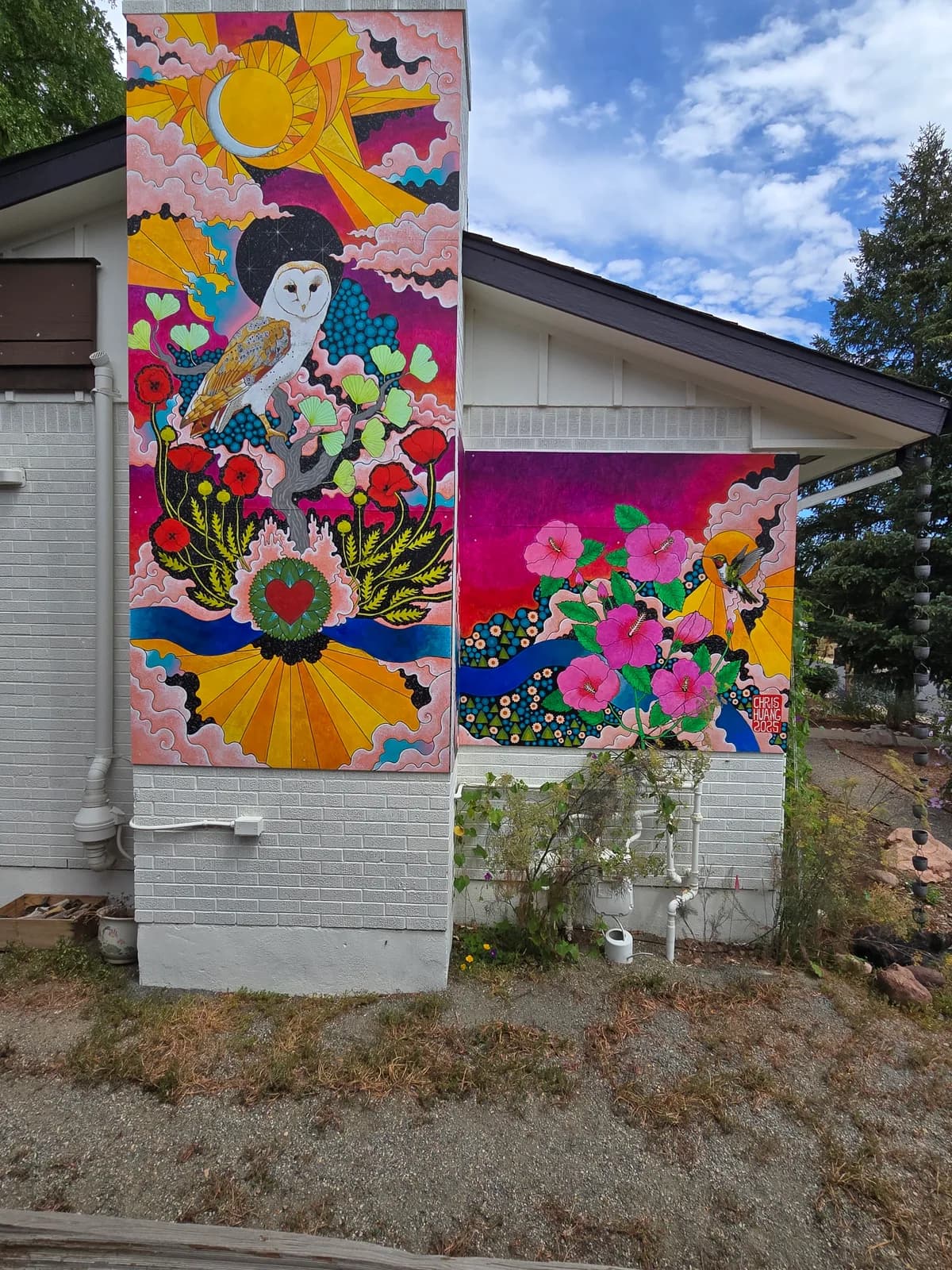 Colorful exterior mural featuring a woman, abundant flowers, and a large sun in vibrant acrylic.