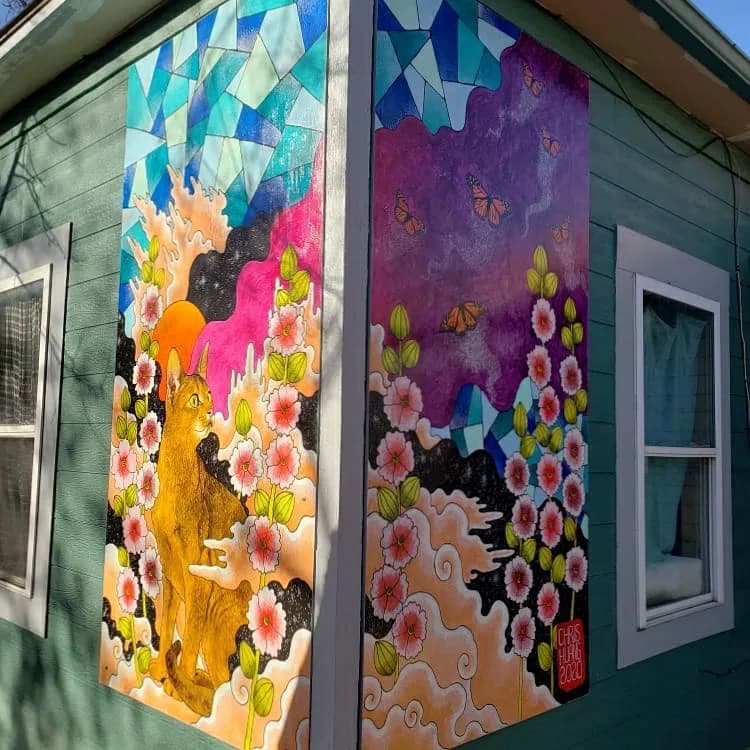 Large-scale mural featuring golden and black animals amid pink blossoms, geometric shapes, and butterfly motifs in acrylic on building panels.