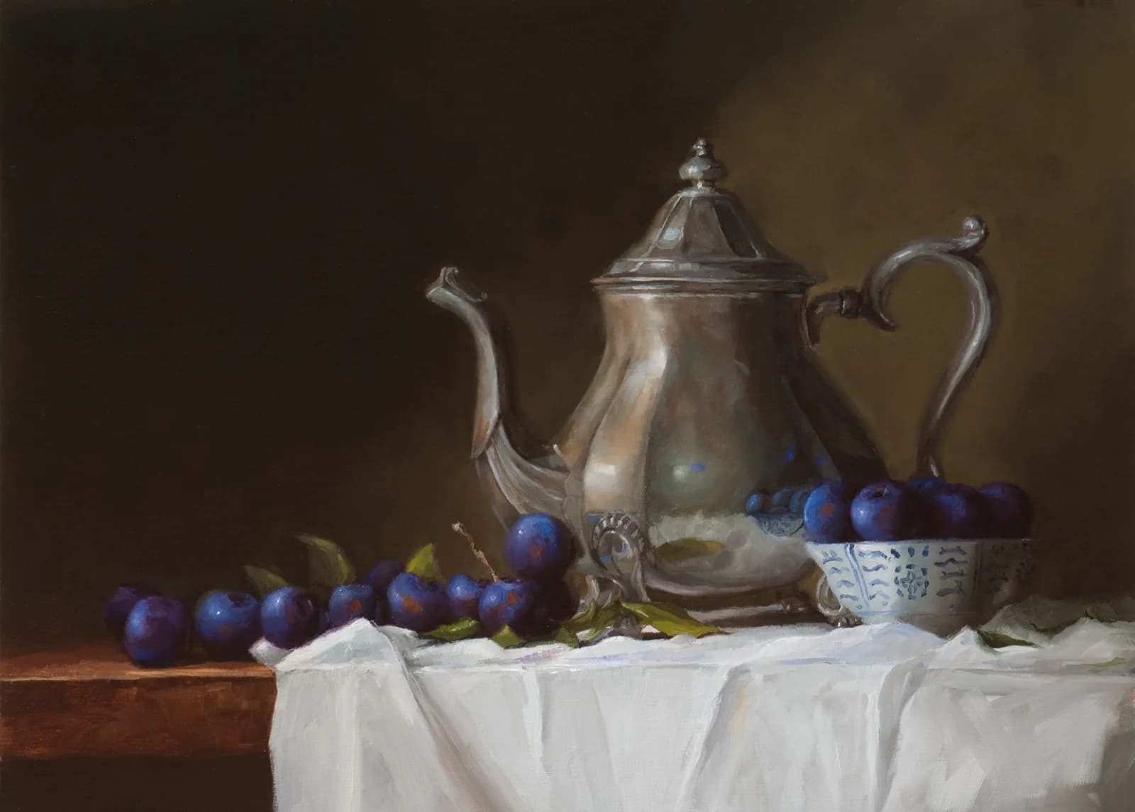 A silver teapot surrounded by blue grapes, a porcelain bowl, and white draped cloth in oil.
