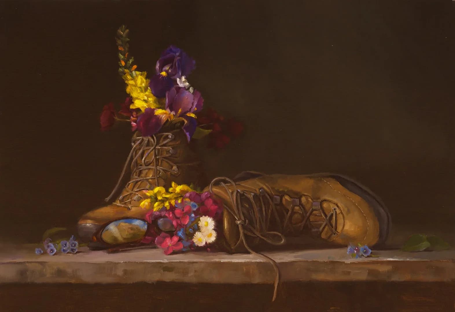 Hiking boots with fresh wildflowers in a vase, arranged on a wooden surface against a dark background.