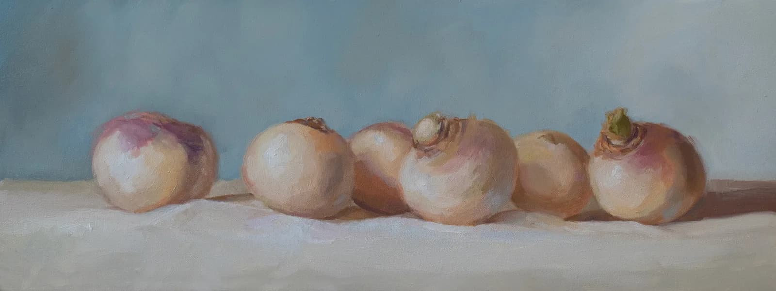 Six onions arranged on a neutral surface against a soft blue-gray background.