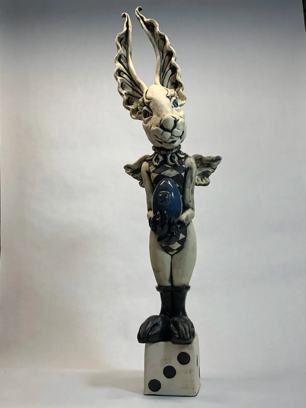 A ceramic stacked-form sculpture depicting a winged figure with turquoise and black glazed components.