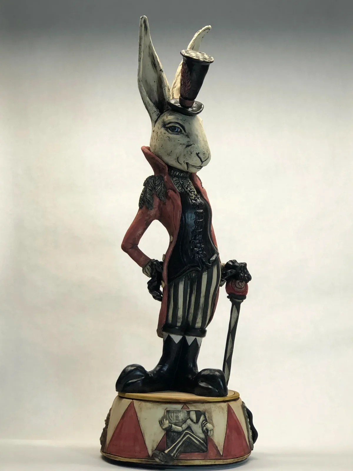 Carved and painted wooden rabbit figurine dressed in formal attire with top hat and sword.