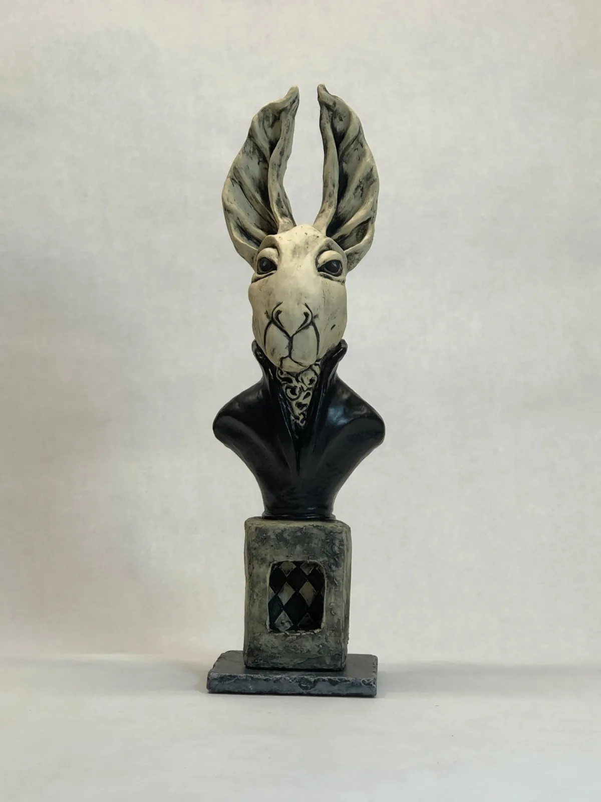 Ceramic sculptural bust of an antelope figure dressed in formal attire with distinctive striped horns.