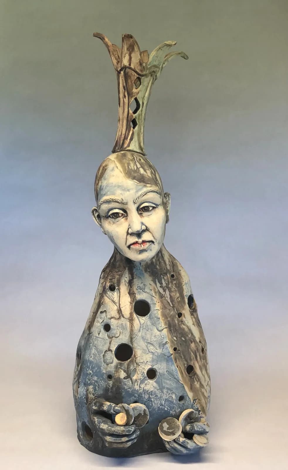 Ceramic sculptural vessel with surreal human head and organic branching form.