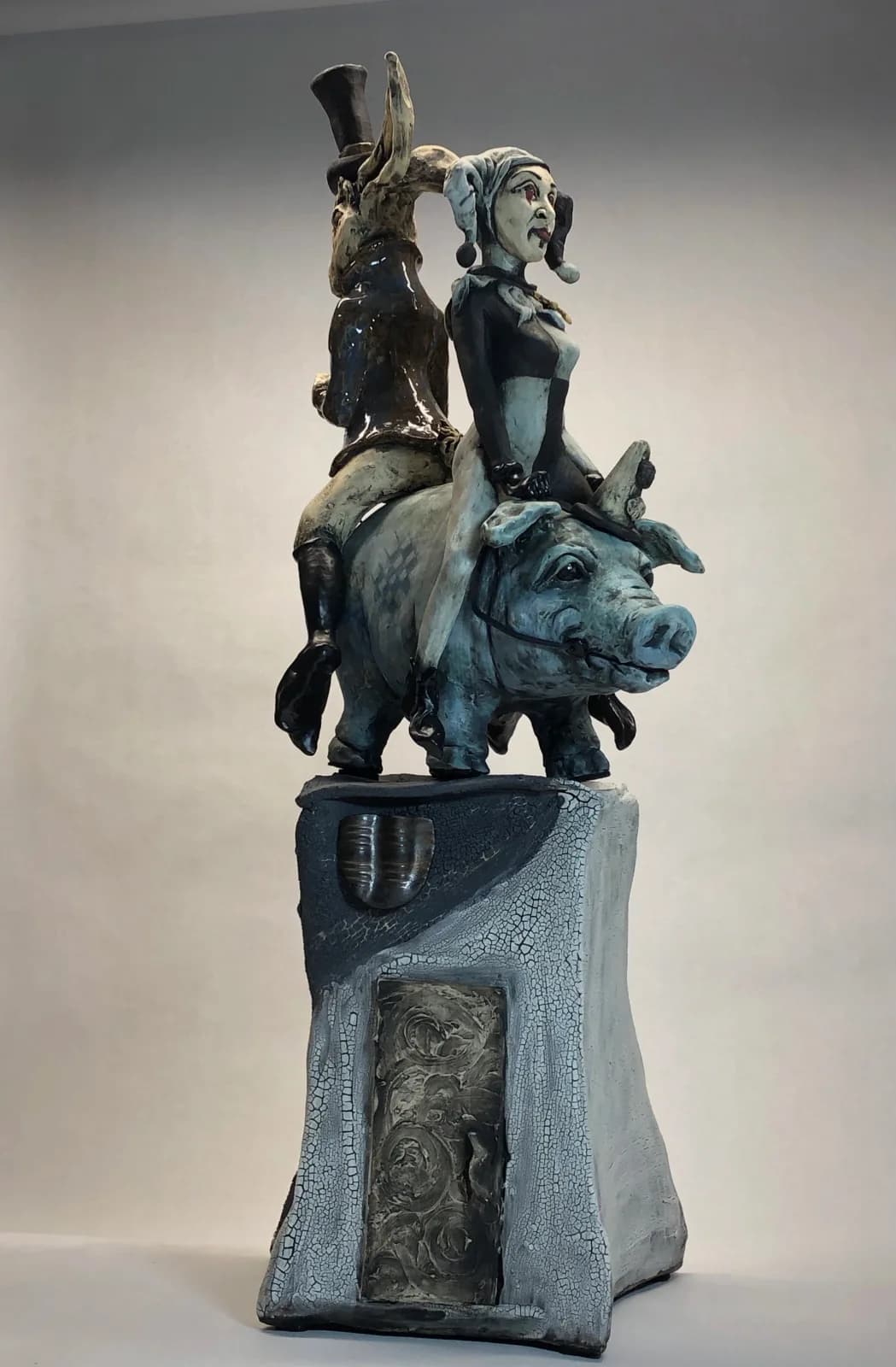 A bronze sculptural assemblage stacks anthropomorphic and animal figures on a textured base, rendered in surreal composition.