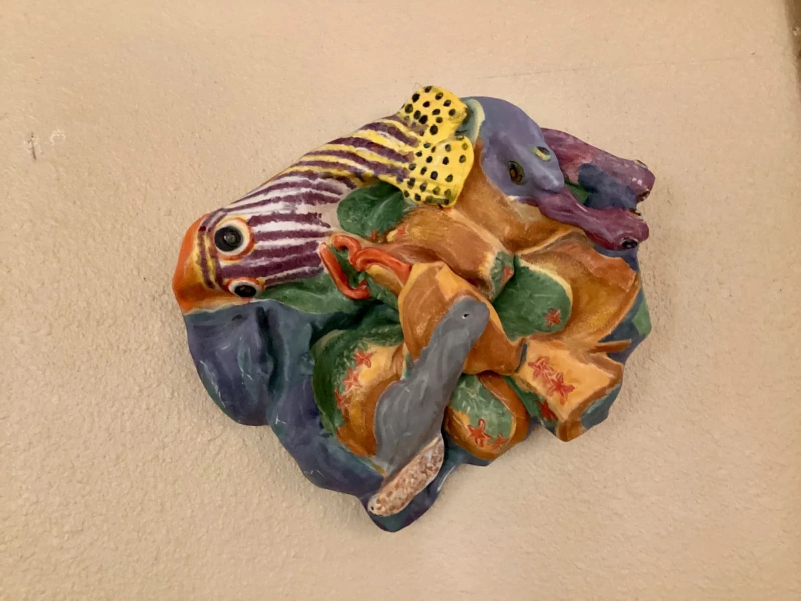 Glazed ceramic relief sculpture depicting stacked colorful fish with contrasting patterns and hand-painted details.
