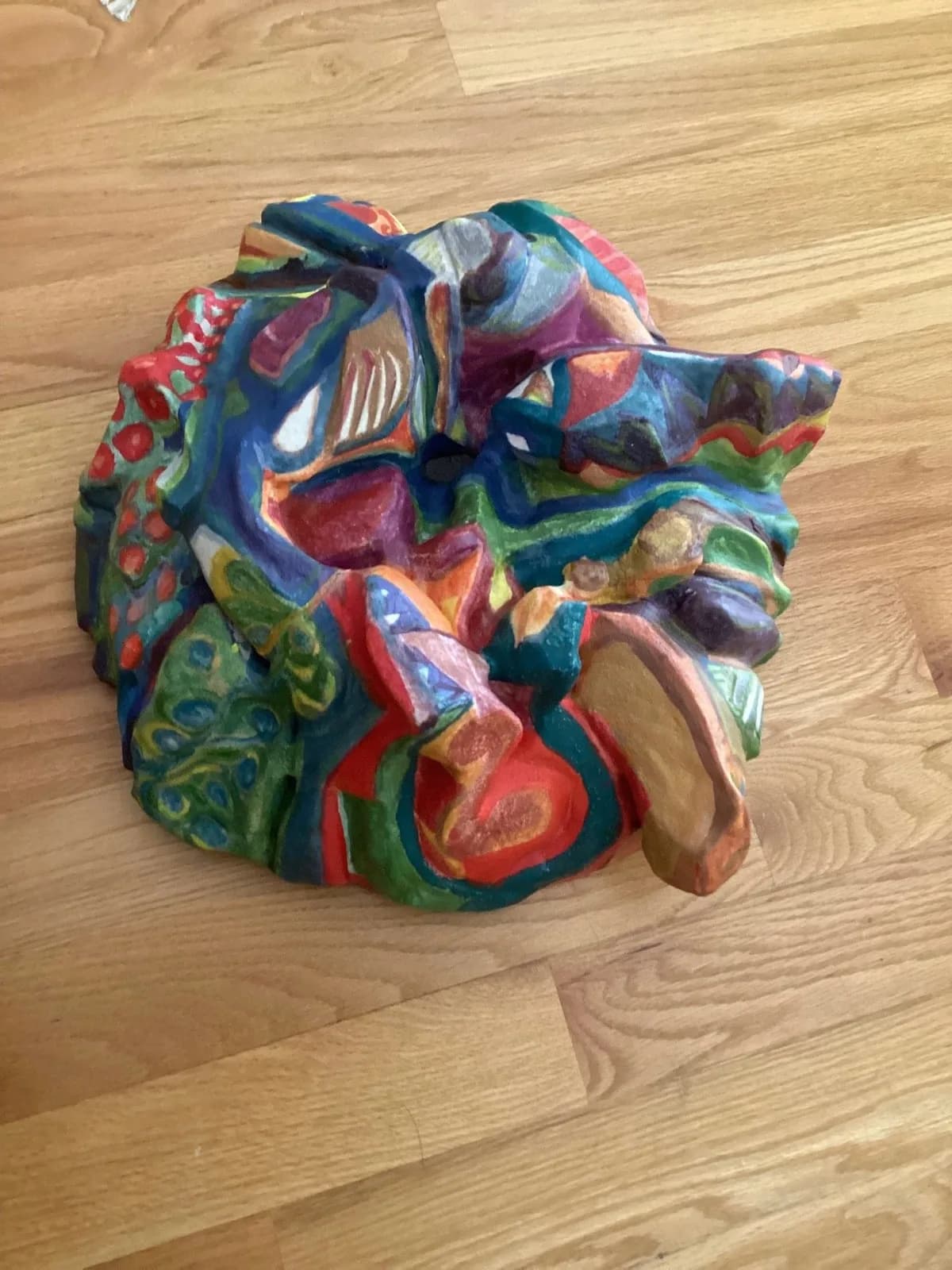 Abstract carved wooden sculpture with vibrant multicolored painted surface, organic geometric forms.