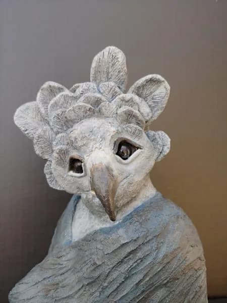 Stone-carved owl head with prominent eyes and textured feather detail.
