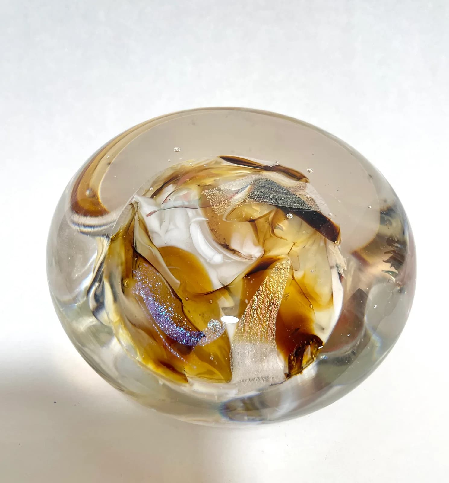 A luminous glass sphere encases a dried insect rendered in amber, brown derby, and mercury tones.