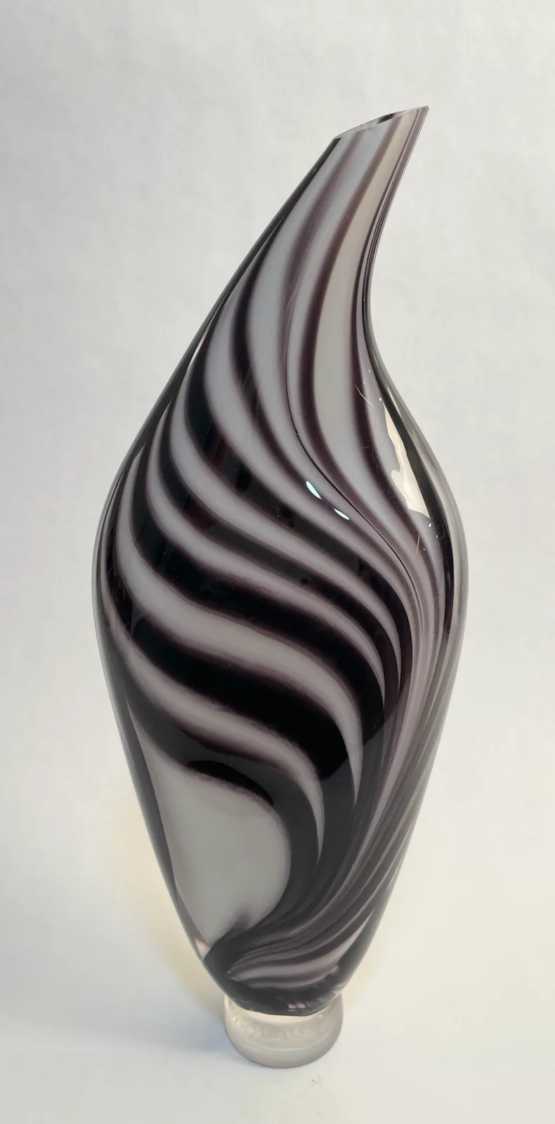 Sculptural glass form with swirling black and gray striations, captured in studio light.