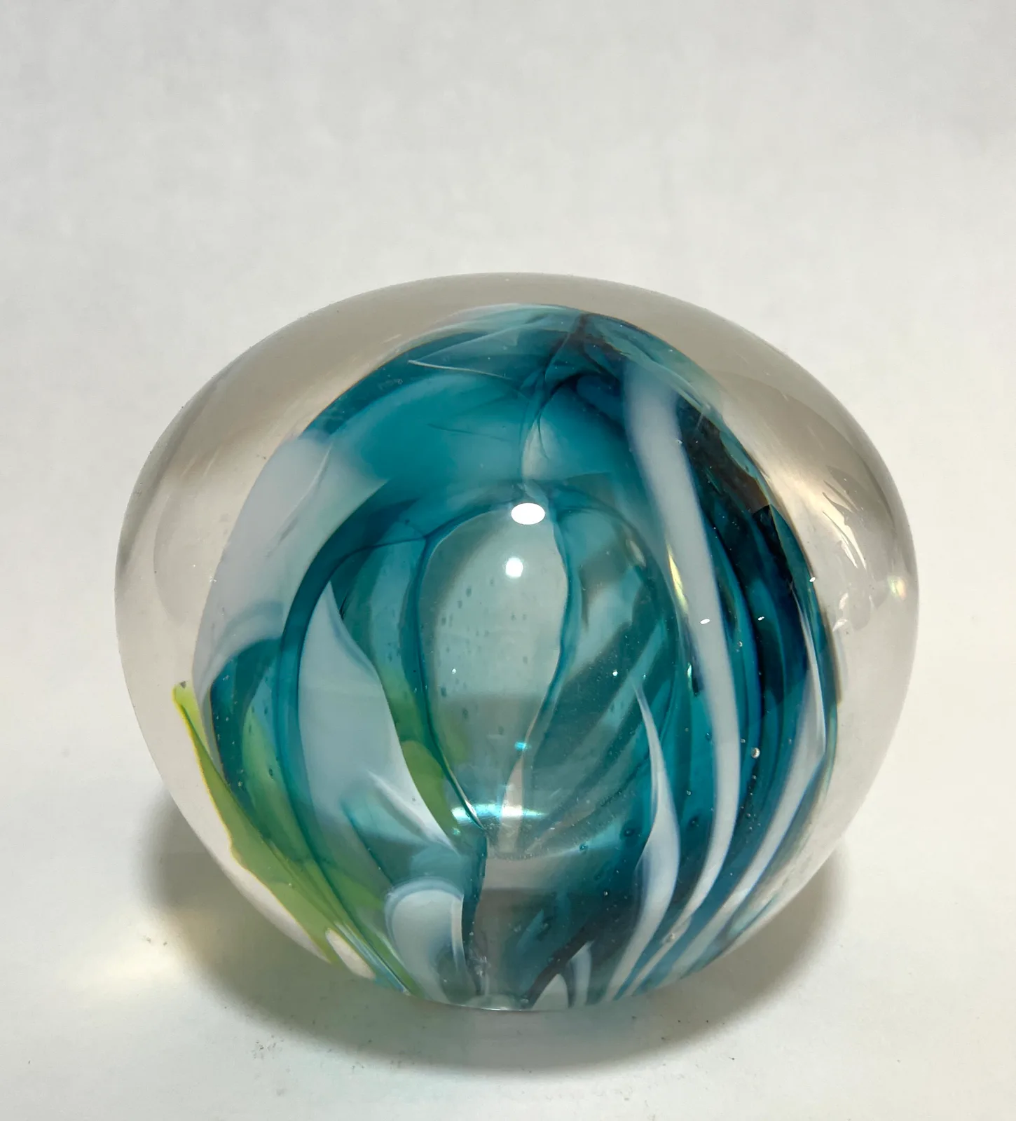 Hand-blown glass sphere with swirling teal and green organic forms suspended within clear glass.