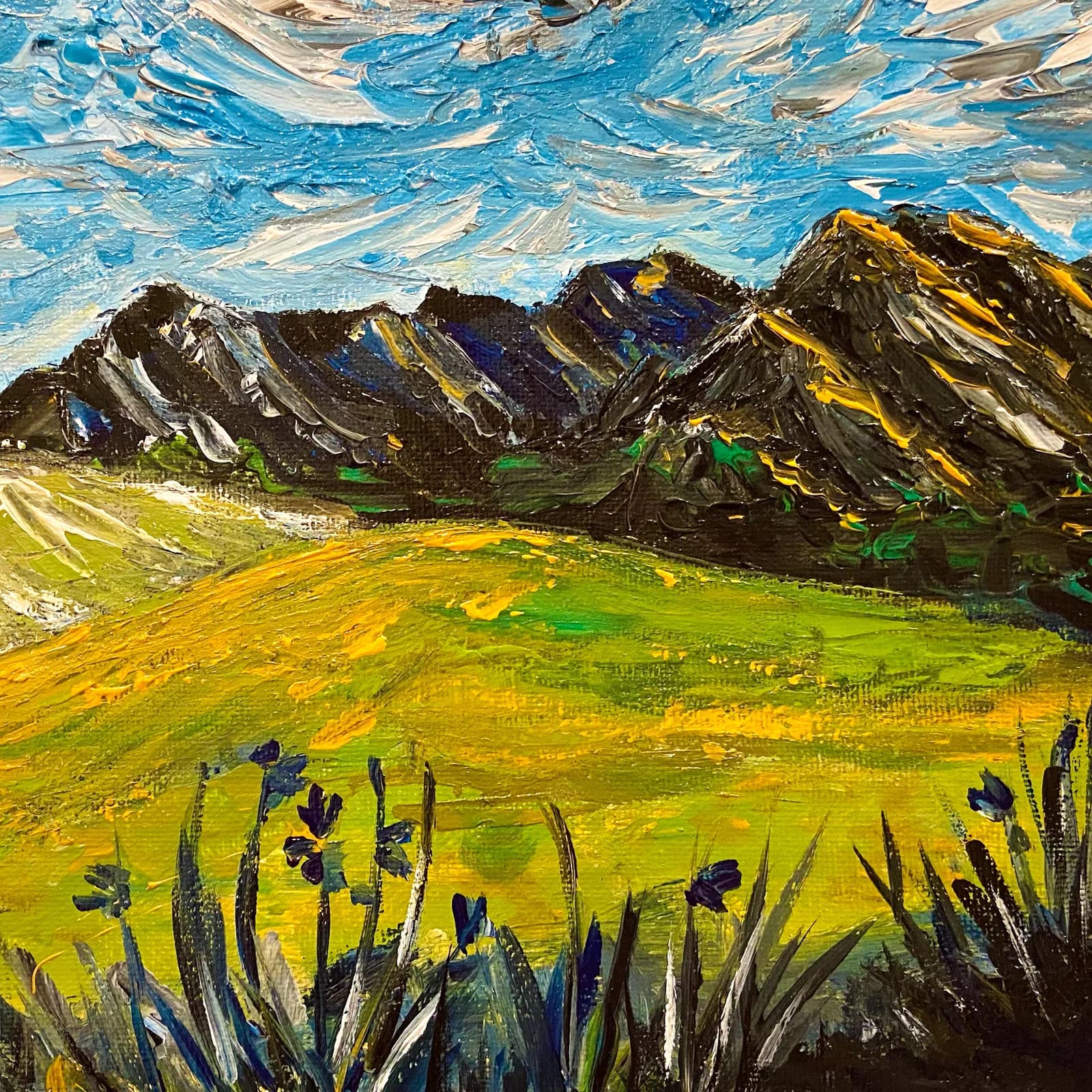 Oil painting of the Boulder Flatirons rising above an alpine meadow dotted with wildflowers and an expressive blue sky.