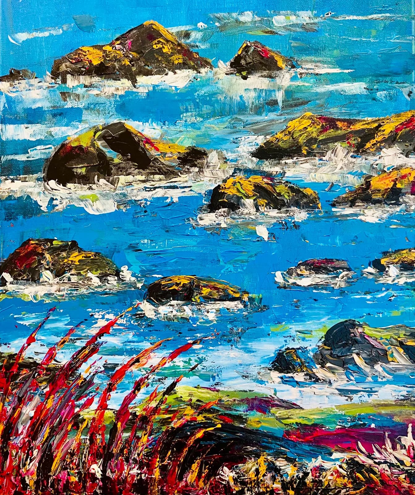 Coastal seascape with golden rocks, turquoise water, and vibrant red foreground flowers in acrylic.